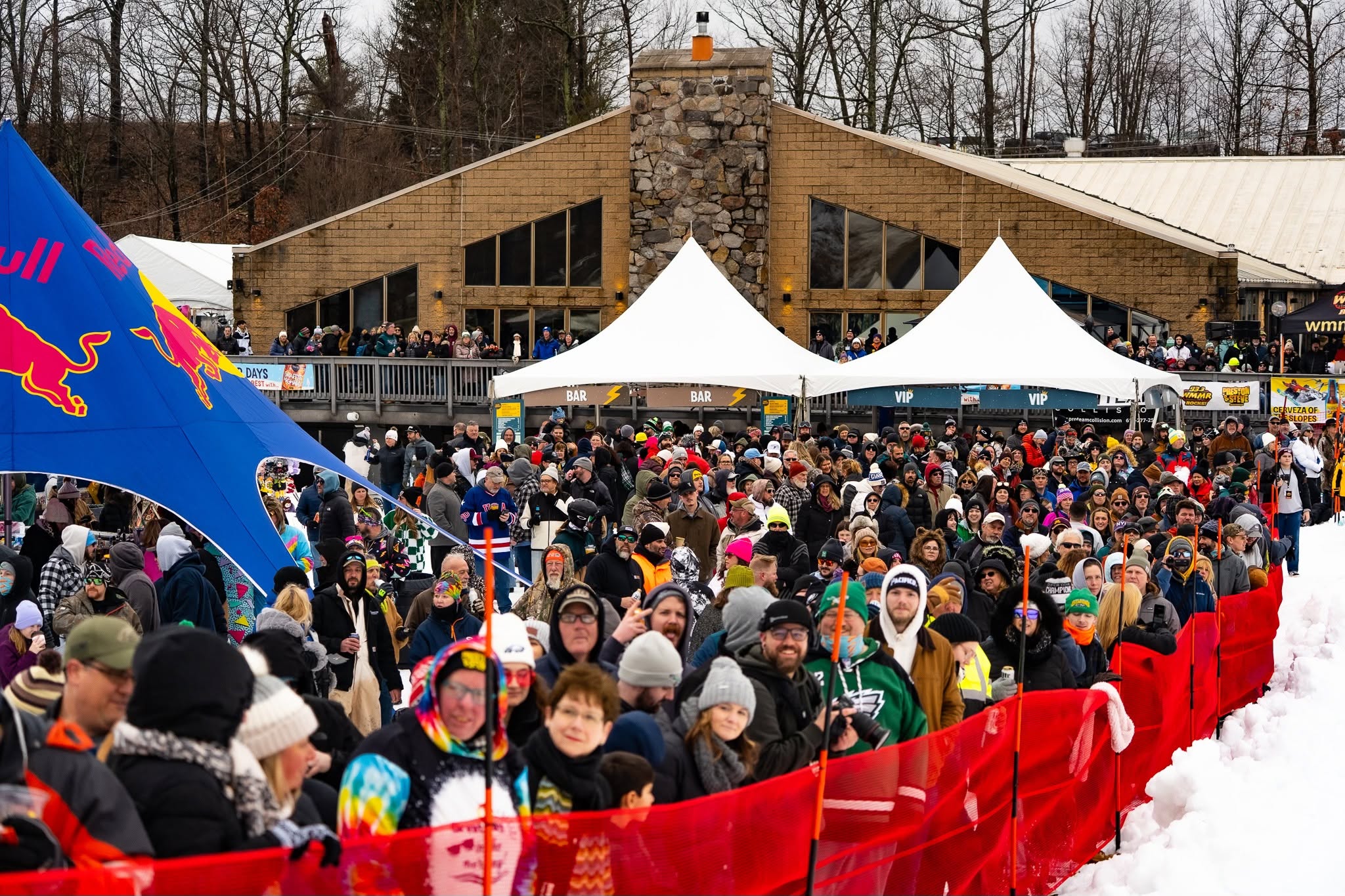 Mountainfest guests filling the snowy event grounds beside the lodge