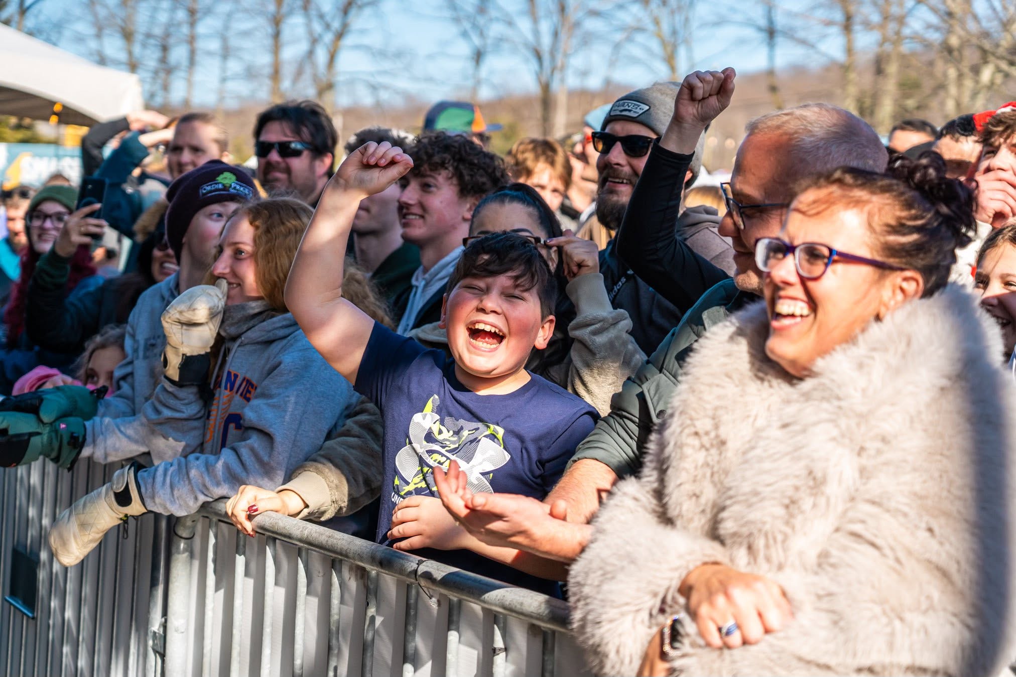 Smiling concert fans cheering from the front of the crowd