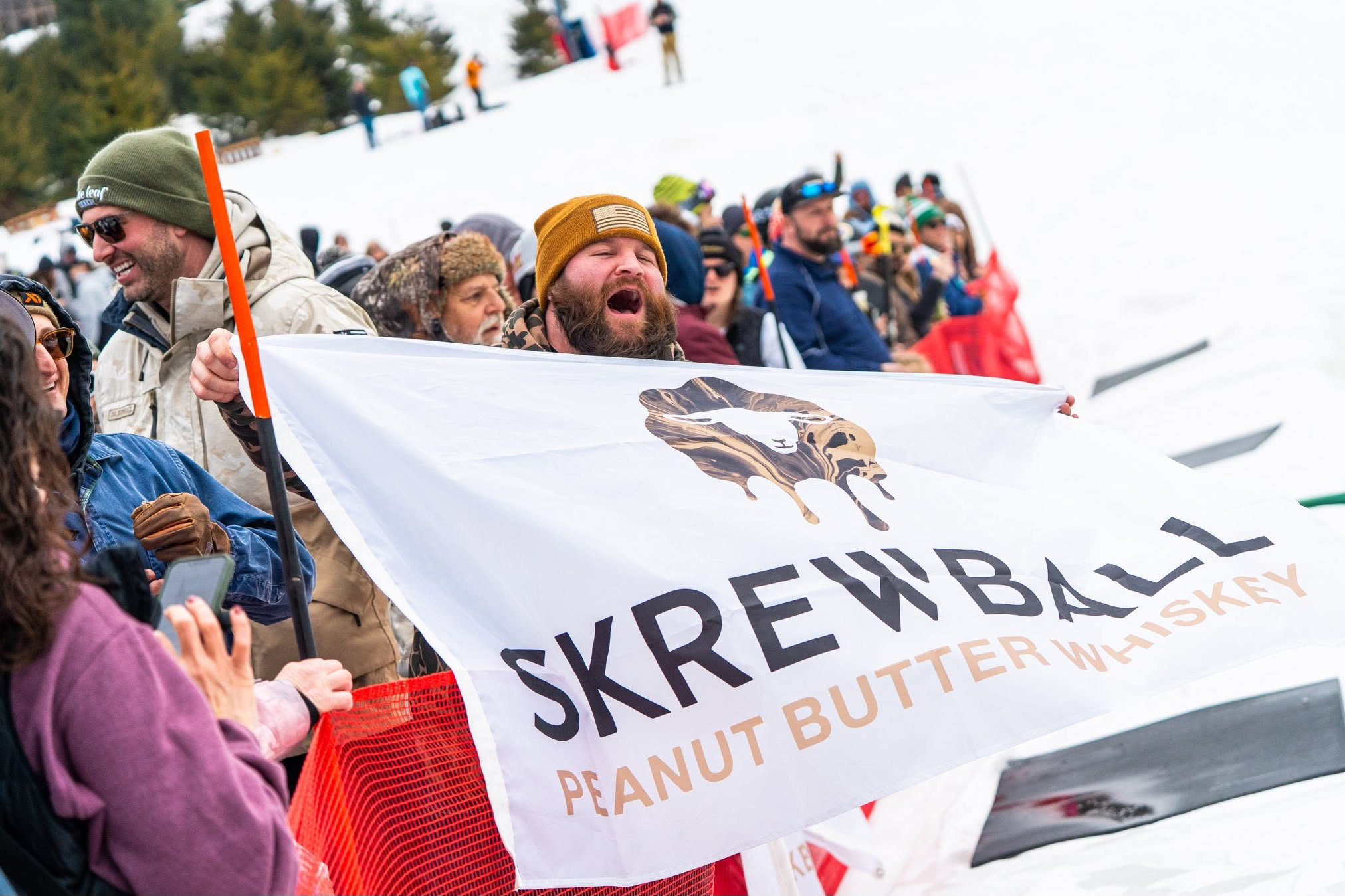 Guests cheering beside a Skrewball sponsor banner at Mountainfest